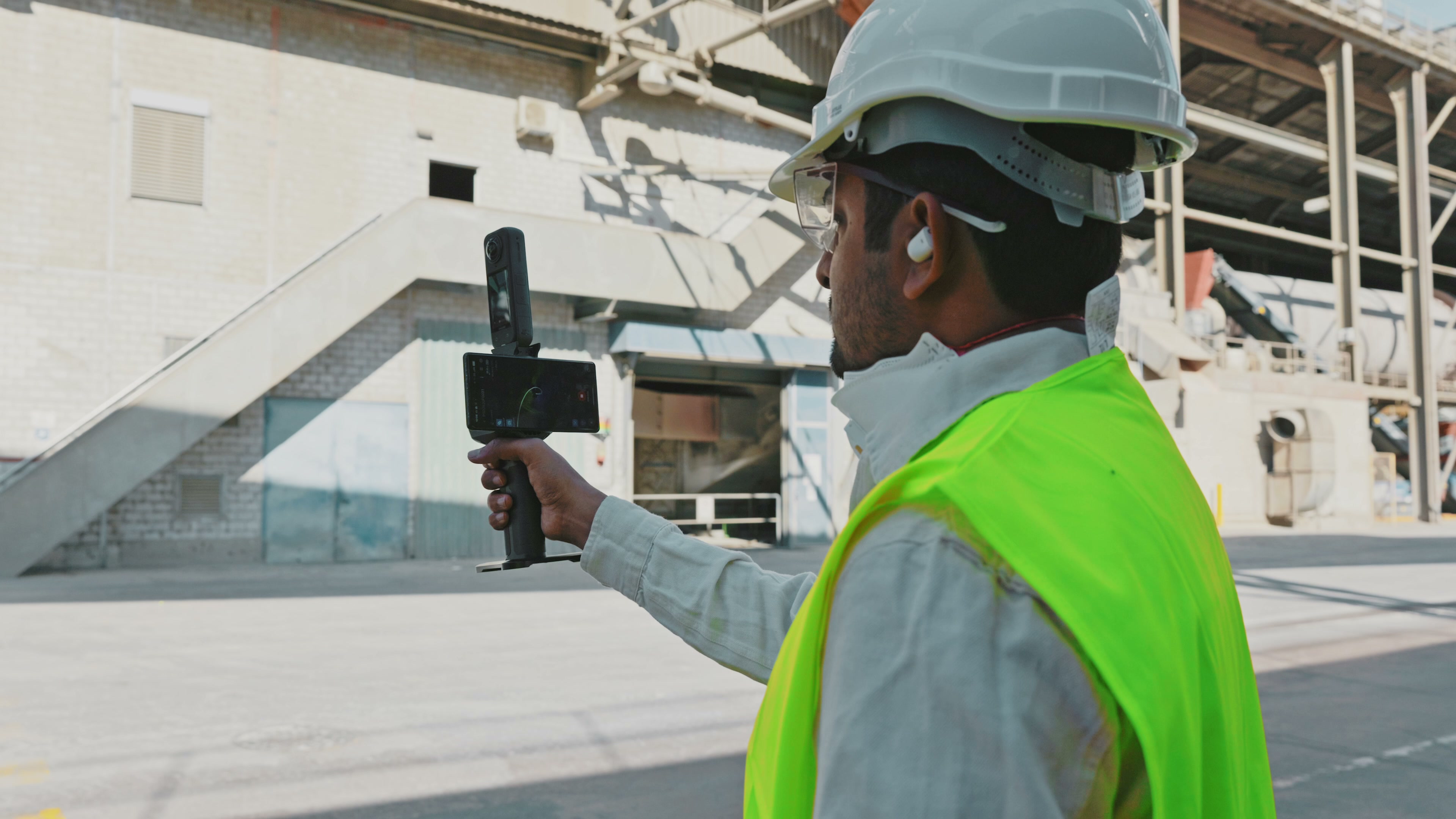 Operator in high-visibility clothing holding an Insta360 camera and mobile capture rig