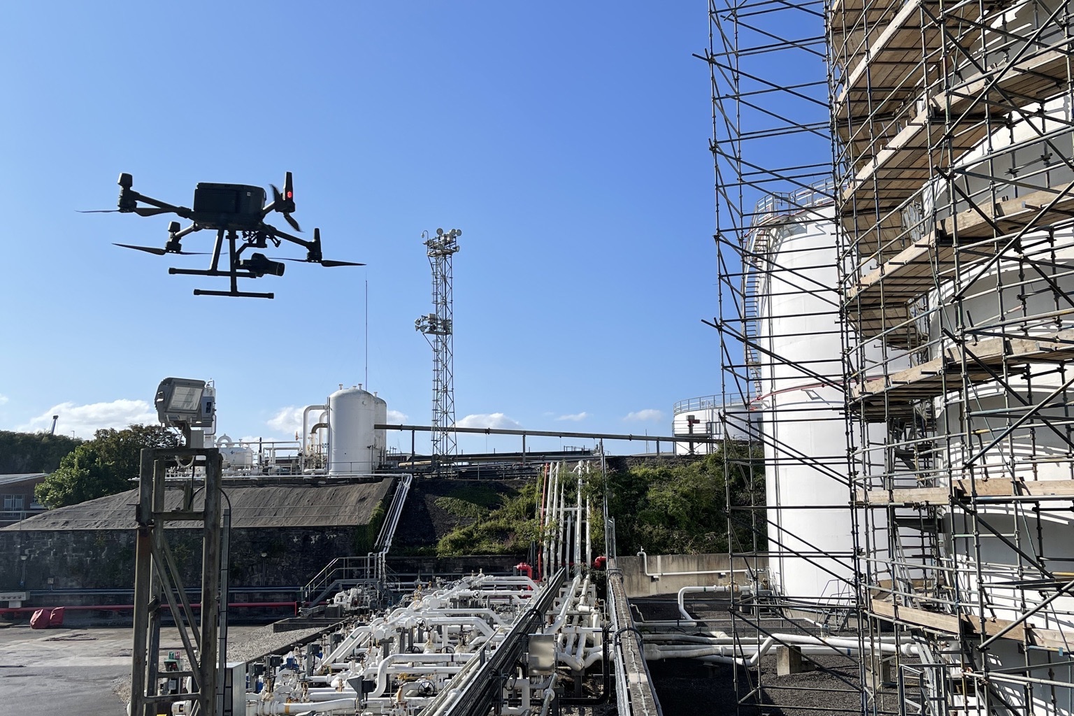 Aerial capture drone flying above dense industrial pipework